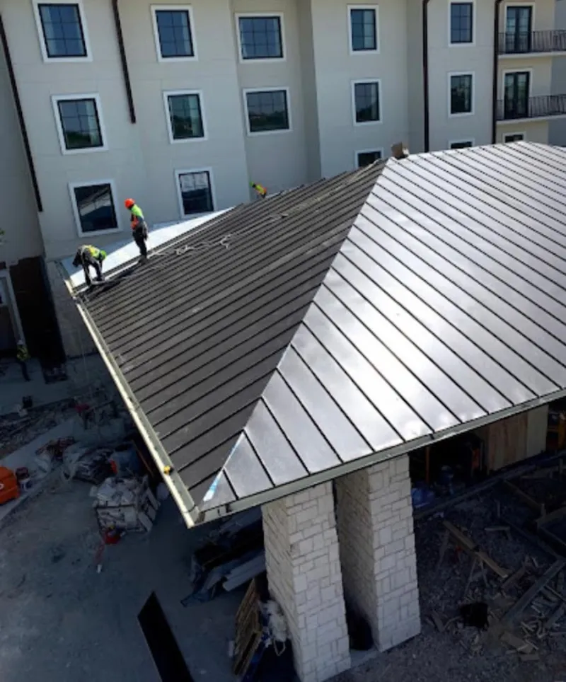 Crew installing standing seam metal roof panels on a commercial project in Branson